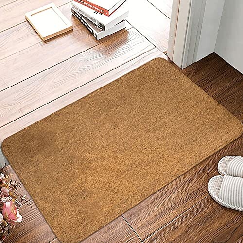 Brown door mat on wooden floor with slippers nearby.