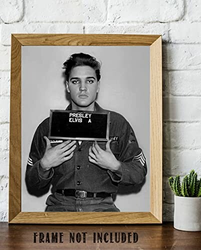 Black and white photo of a young man holding a name board.